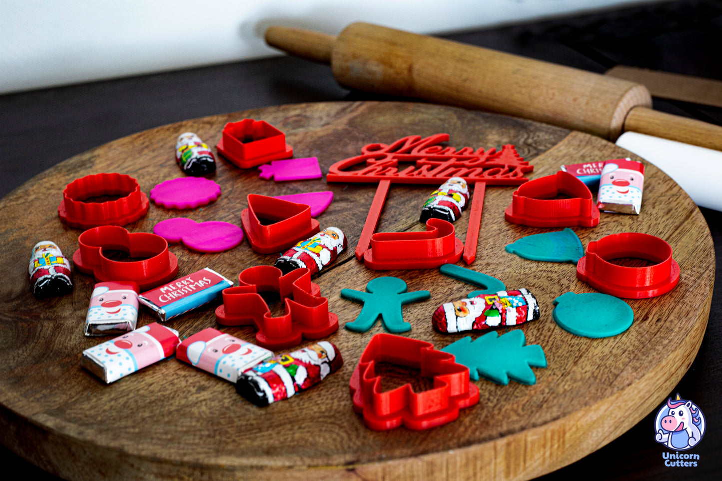 Set of mini Christmas cookie cutters, including a cake topper saying Merry Christmas. The scene is decorated with mini Christmas chocolates